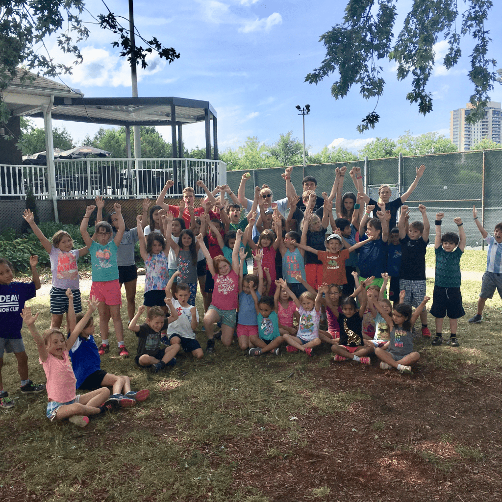 children outside, happy, with arms in the air at sports camp