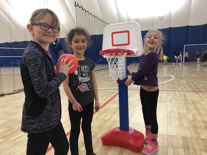 three girls playing basketball at sports camp