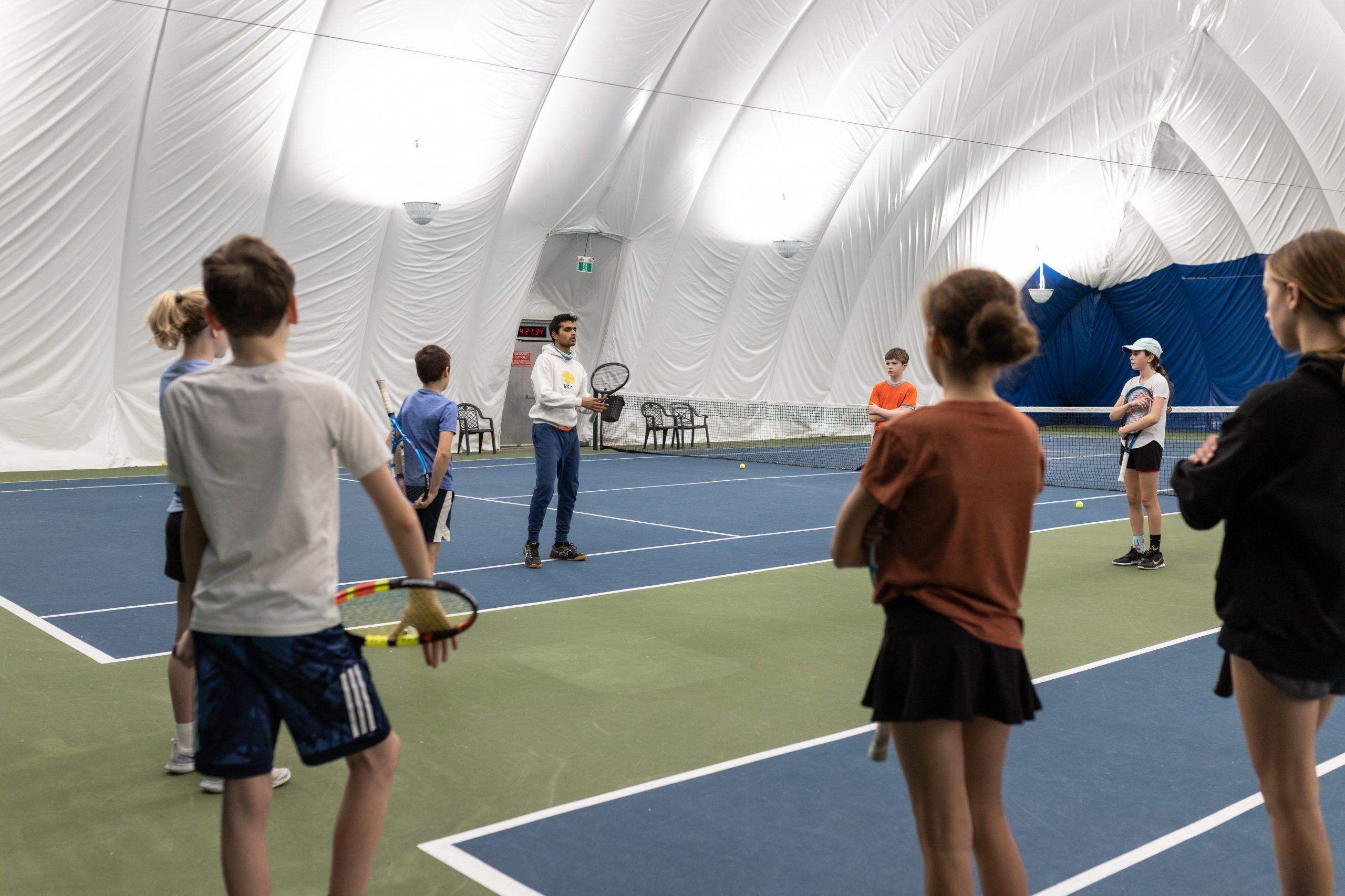 kids being instructed by tennis pro