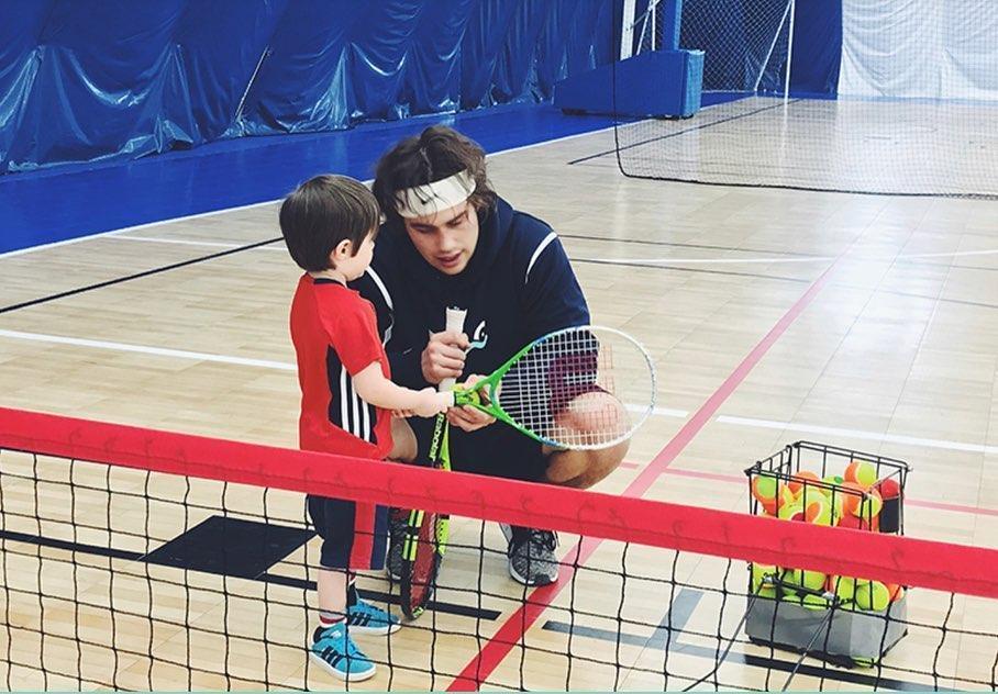 toddler learning tennis in a gym