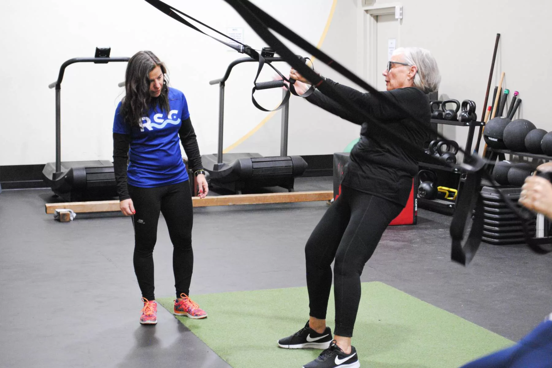 a TRX instructor teaching a women during a fitness class