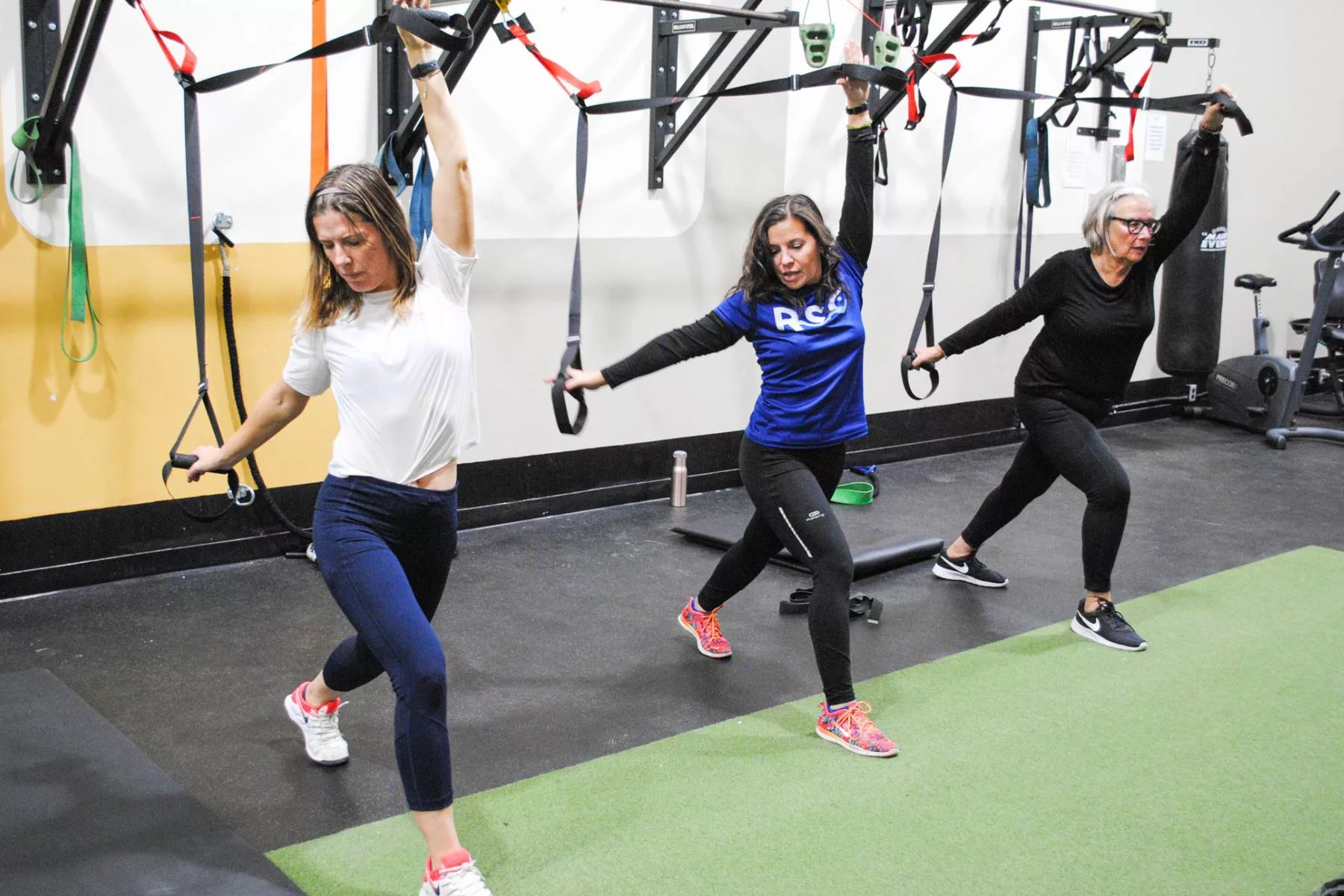 three women doing a TRX fitness class