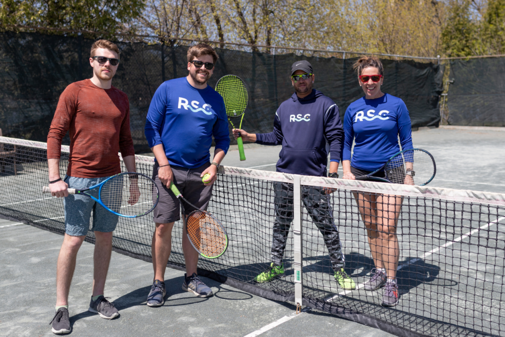 three middle ages men and one women with summer tennis pass enjoying tennis on outdoor clay court in ottawa